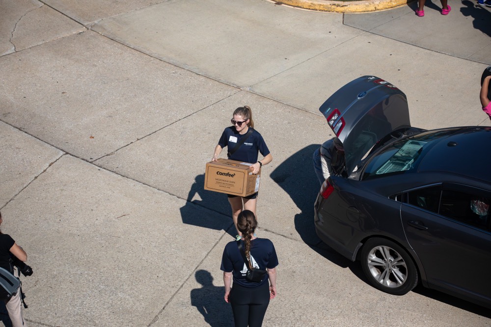 Birds Eye view of GVSU alumna unloading a cardboard box out of car